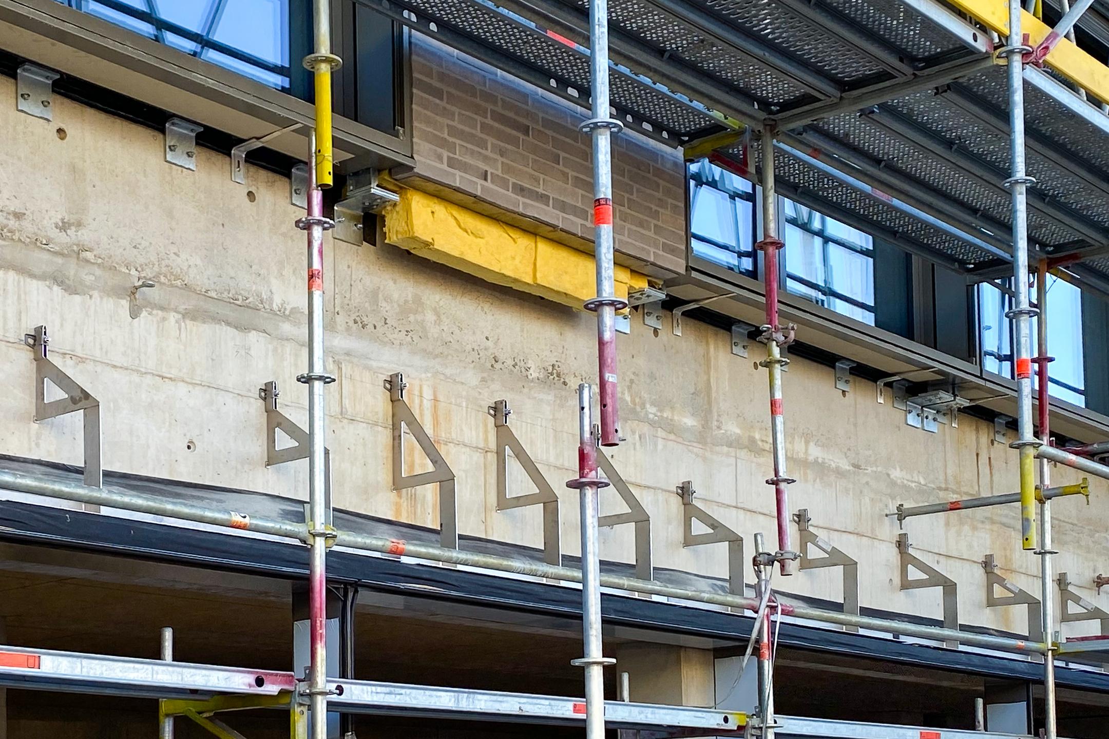 Verblenderkonsolen an Betonwand mit Baugerüst