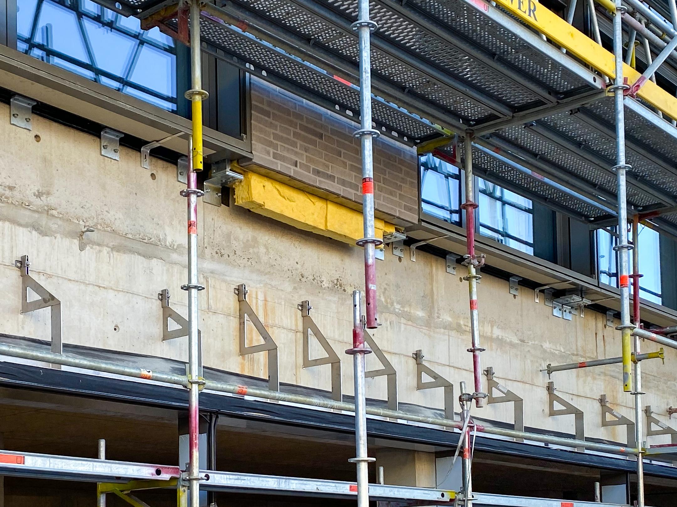Verblenderkonsolen an Betonwand mit Baugerüst