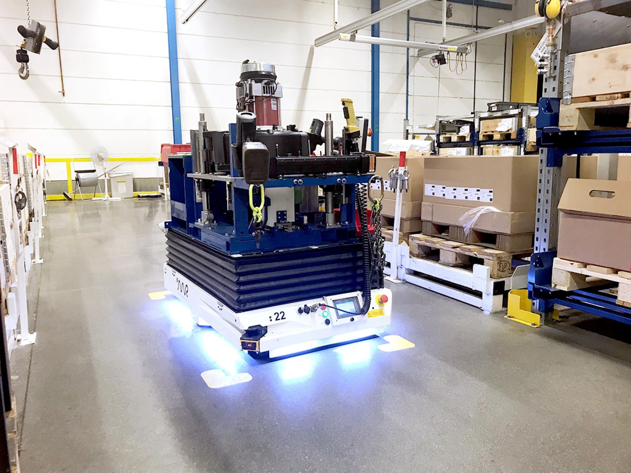 Automatisierter Transportroboter bewegt Waren durch eine Halle mit Regalen und Kartons