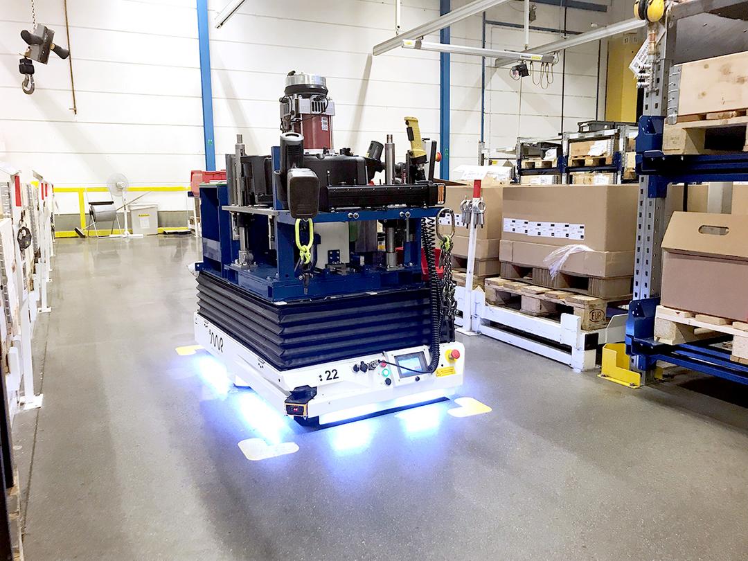 Automatisierter Transportroboter bewegt Waren durch eine Halle mit Regalen und Kartons