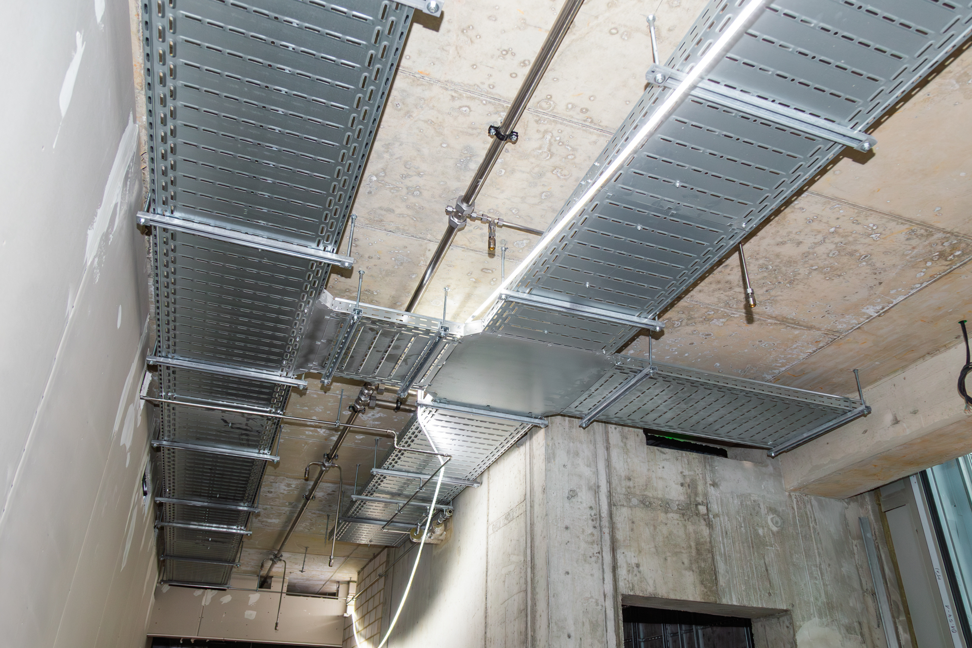 An der Decke montierte Kabeltrassen mit Kreuzung und Lichtschlauch zur Baustellenbeleuchtung