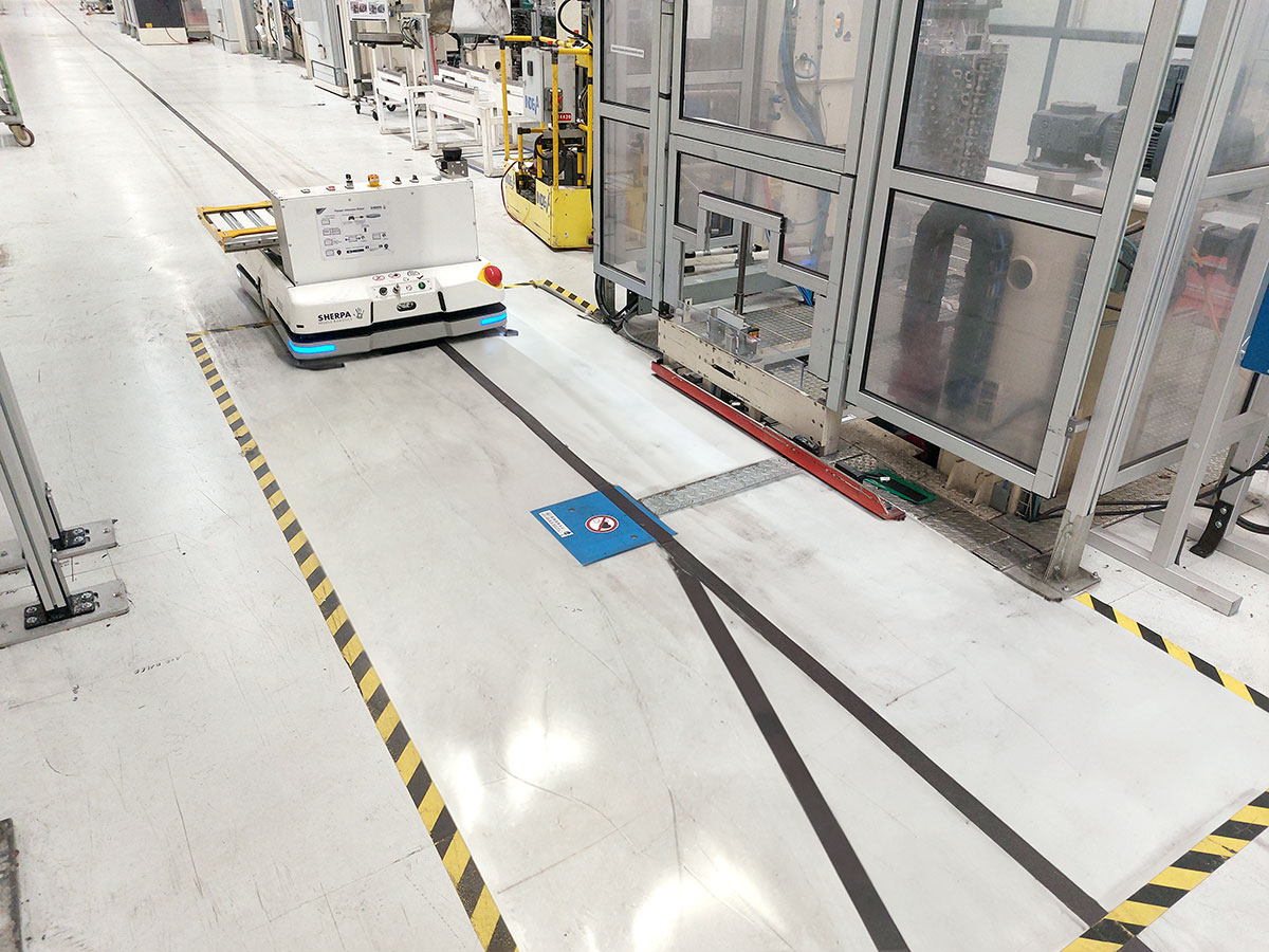 Automatisierter Transportroboter auf einem markierten Industrieboden mit induktiver Ladeeinbaueinheit im Boden